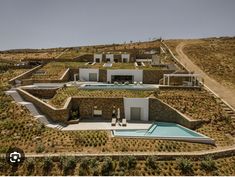 an aerial view of a house with a swimming pool in the foreground and lots of greenery on the hillside