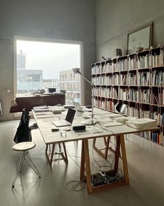 a room with many bookshelves and desks in front of a large window