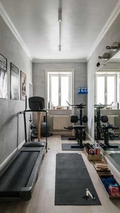 a home gym with treadmills, exercise mats and mirrors in the wall next to each other