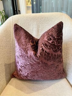 a purple pillow sitting on top of a white chair