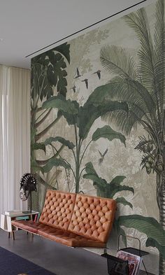 a couch sitting in front of a wall with plants on it