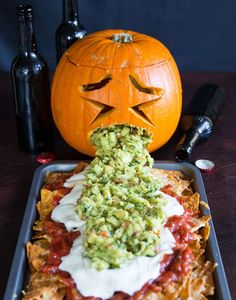 a halloween pumpkin with guacamole on top and chips in the foreground