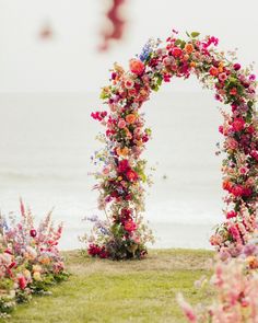 an archway made out of flowers near the ocean