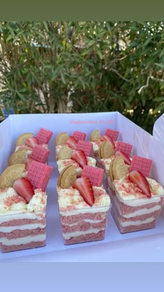 there are many desserts in the box on the table with strawberries and crackers