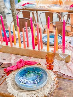 the table is set with colorful candles and place settings for an outdoor dinner or party