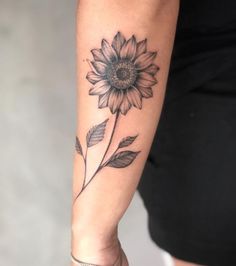 a woman's arm with a sunflower tattoo on it