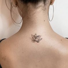 the back of a woman's neck with a lotus tattoo on it