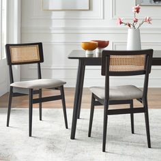 two chairs sitting at a table with a vase and bowl on top of the table