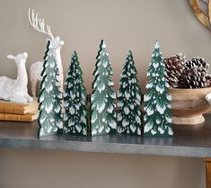 small wooden trees are sitting on a shelf next to pine cones and deer figurines