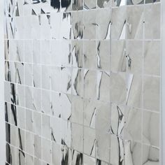 a white tiled wall with some black and white tiles on the bottom right hand corner