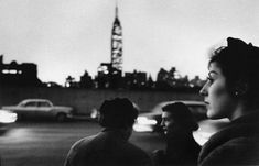 black and white photograph of two women standing in front of a city street at night