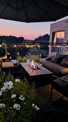 a living room with couches, tables and an umbrella over the fire pit at dusk