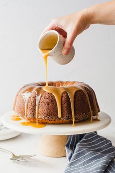 someone drizzling icing on a bundt cake with caramel sauce