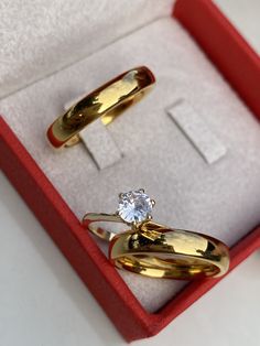 two gold rings in a red box with a white diamond on the top and bottom