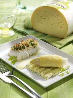 a white plate topped with food next to a bottle of wine and a fork on top of a green table cloth