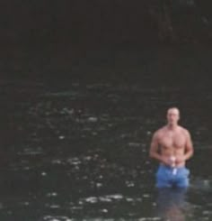 a man standing in the middle of a body of water wearing blue trunks and no shirt