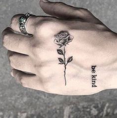 a person's hand with a rose tattoo on it