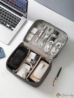 an open laptop computer sitting on top of a desk next to a bag filled with electronics