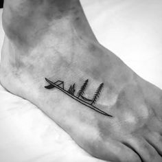 a small tattoo on the foot of a person with trees and a surfboard in it