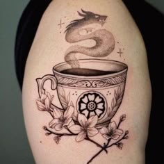 a woman with a tattoo on her arm has a cup of coffee in the shape of a dragon