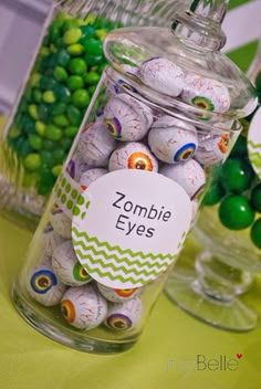 a jar filled with lots of candy sitting on top of a table next to green and white candies