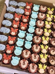 a box filled with lots of cupcakes covered in fondant monkey and giraffe faces