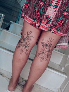 a woman's legs with tattoos on them and flowers on the bottom part of her leg