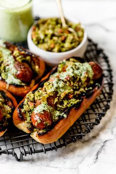 three hot dogs with toppings on a wire rack next to a green smoothie