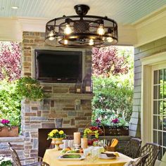 an outdoor dining area with table, chairs and television on the wall above fire place