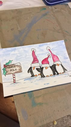 two penguins wearing santa hats and one penguin is holding a sign that says mom's pole