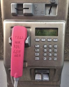 an old payphone with writing on it that says tell her you've loved her