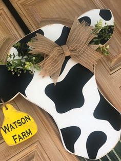 a cow shaped door hanger with a bow on it