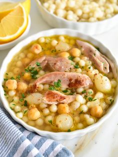 a white bowl filled with soup next to a lemon slice and some other food items