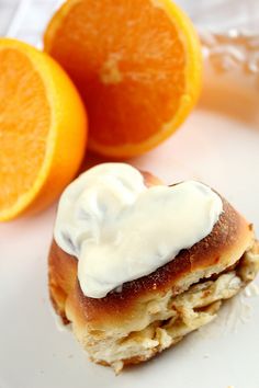 an orange and pastry with icing on a white plate next to two oranges