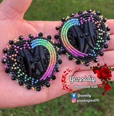 there is a pair of earrings made out of black and multicolored seed beads