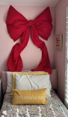 a bed with a red bow on the headboard and pillows in front of it