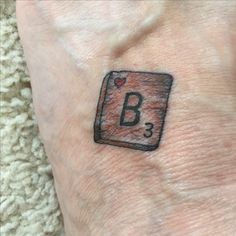 a small tattoo on the wrist of a person's left arm, which has a b in it