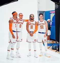 three basketball players are standing in front of a camera while wearing orange and white uniforms