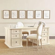 a white desk with two chairs and three pictures on the wall