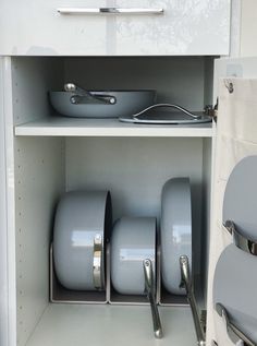 an open cabinet filled with pots and pans