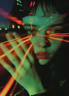 a woman holding her hand up to her face with neon lights coming out of it