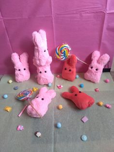 stuffed animals and candy on a table with pink paper behind them, including lollipops