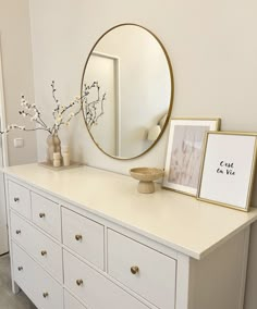 a white dresser topped with a mirror and vase filled with flowers