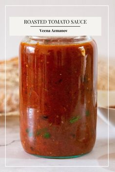 roasted tomato sauce in a glass jar on a table with bread behind it and text overlay that reads roasted tomato sauce