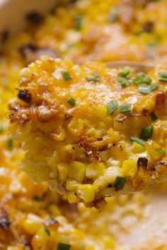 a close up of a spoon full of corn casserole with green onions on it