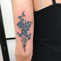 a woman's arm with a blue flower tattoo on the left side of her arm