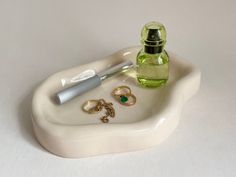 a small white tray with rings and a pen on it next to a green bottle