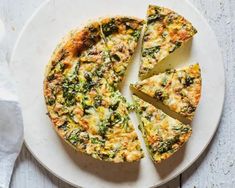 a white plate topped with a quiche covered in cheese and spinach toppings