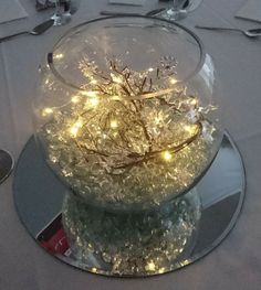 a snow globe with lights in it sitting on top of a white tablecloth covered table