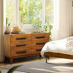 a bedroom with a bed, dresser and plants in the window sill next to it